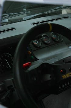 Close-up view of a sports car dashboard, featuring gauges and a steering wheel.