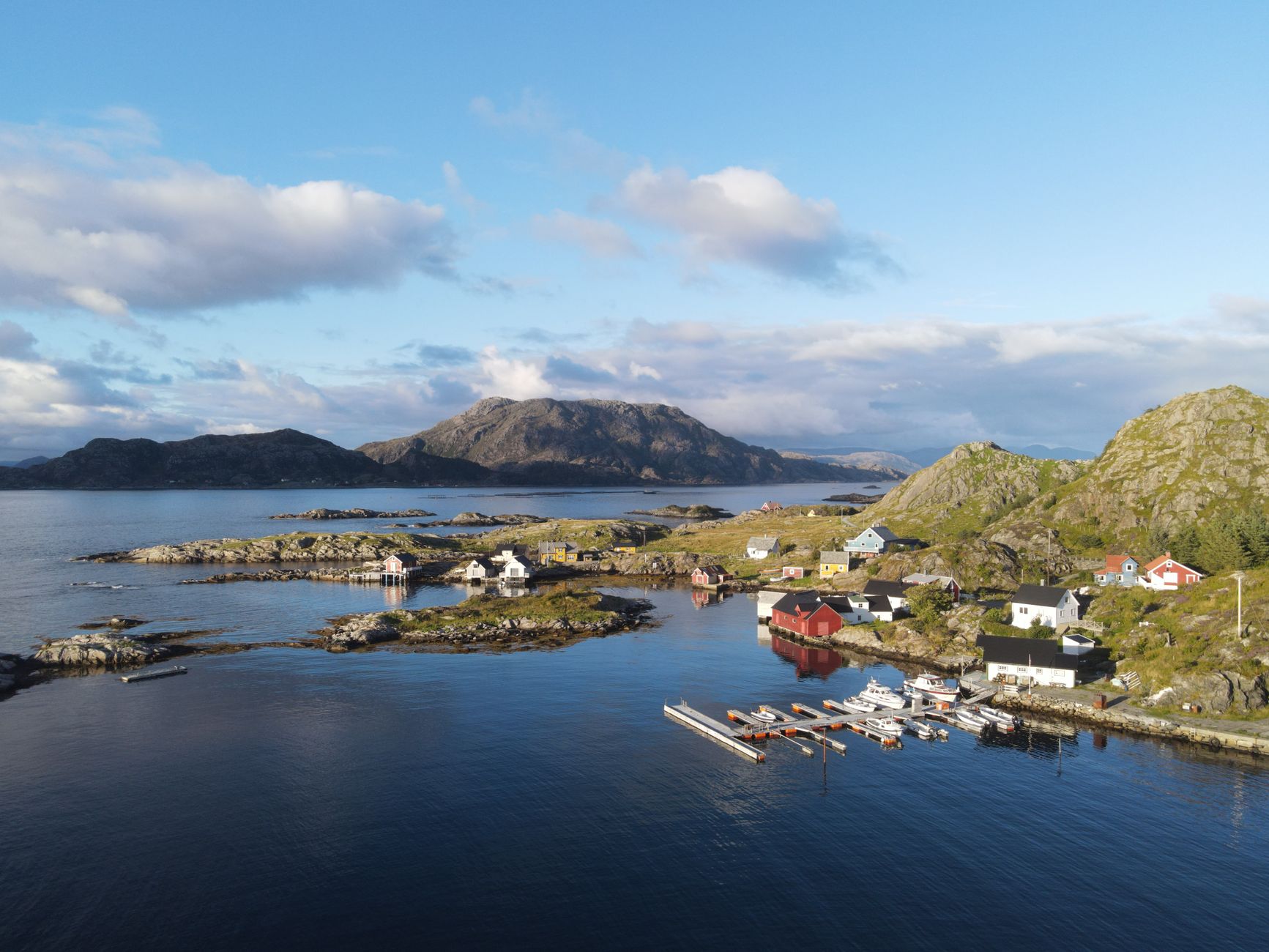 Stunning aerial view of Kinn, Nordland, Norway showcasing coastal islands, mountains, and vibrant houses.