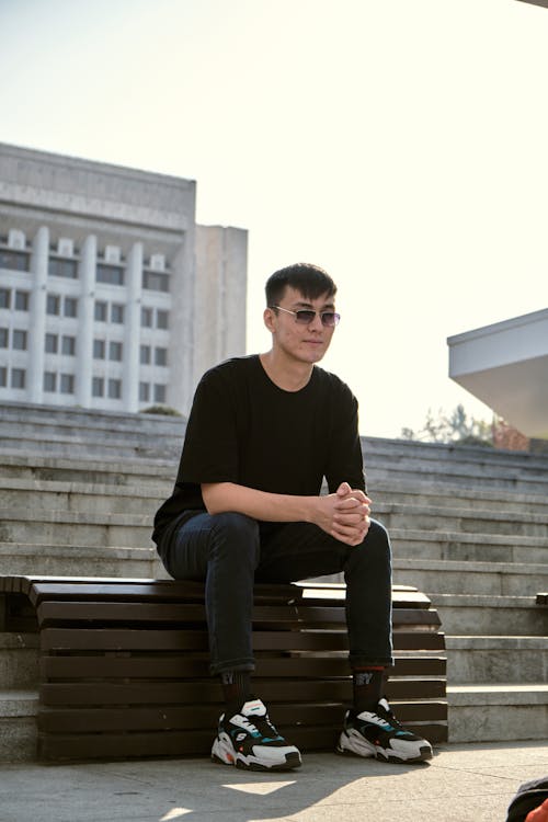 Free A Man in Black Shirt Sitting on a Wooden Bench Stock Photo