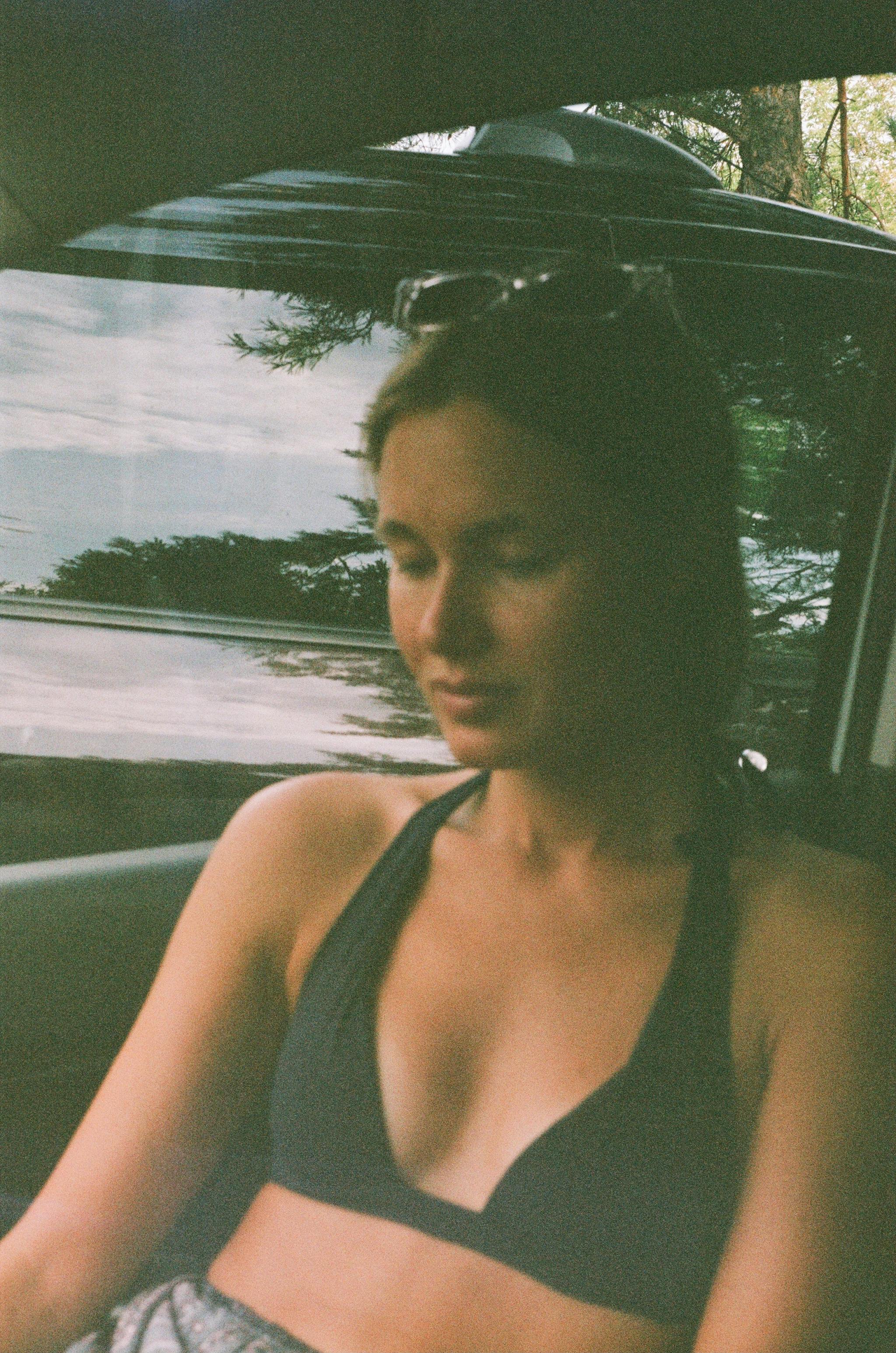 Relaxed woman in bikini top sitting inside a car on a summer day