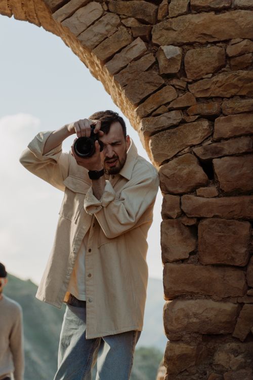 Free Man takes photos near rustic stone arch in natural outdoor setting. Stock Photo