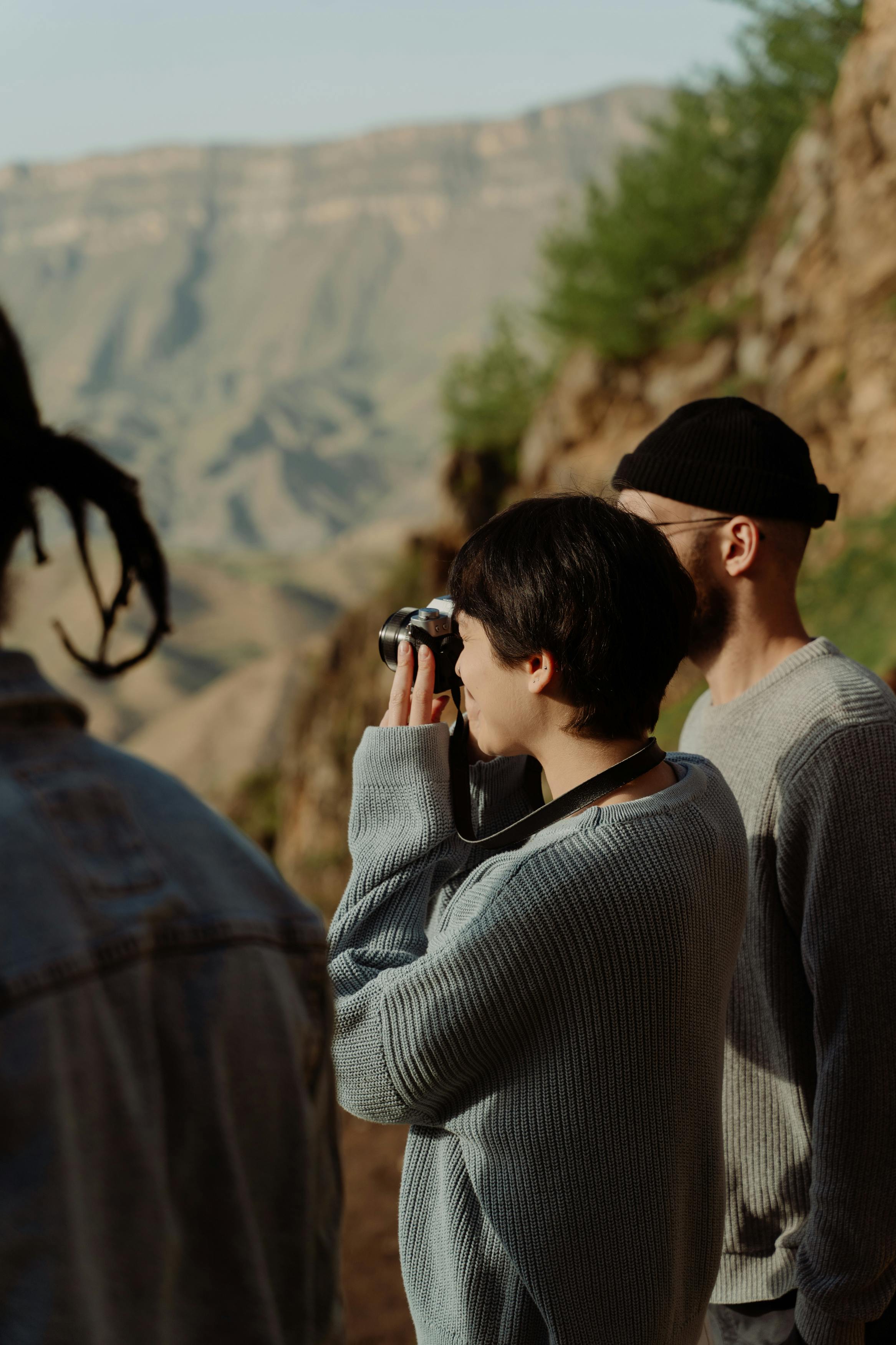 a woman in a gray sweater taking a picture with a camera