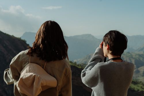 Free Two friends enjoying a stunning mountain view, capturing the moment in an outdoor adventure. Stock Photo