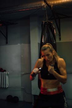A determined female boxer training indoors with a punching bag, showcasing strength and focus.