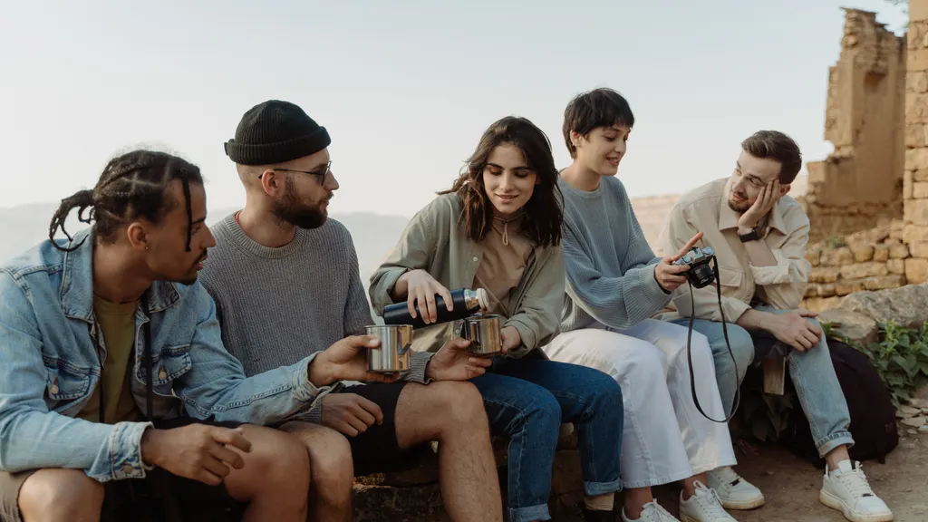 Group of friends sitting on a bench outdoors with drinks