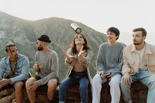 Free Friends relaxing on a mountain enjoying the view and having fun together. Stock Photo