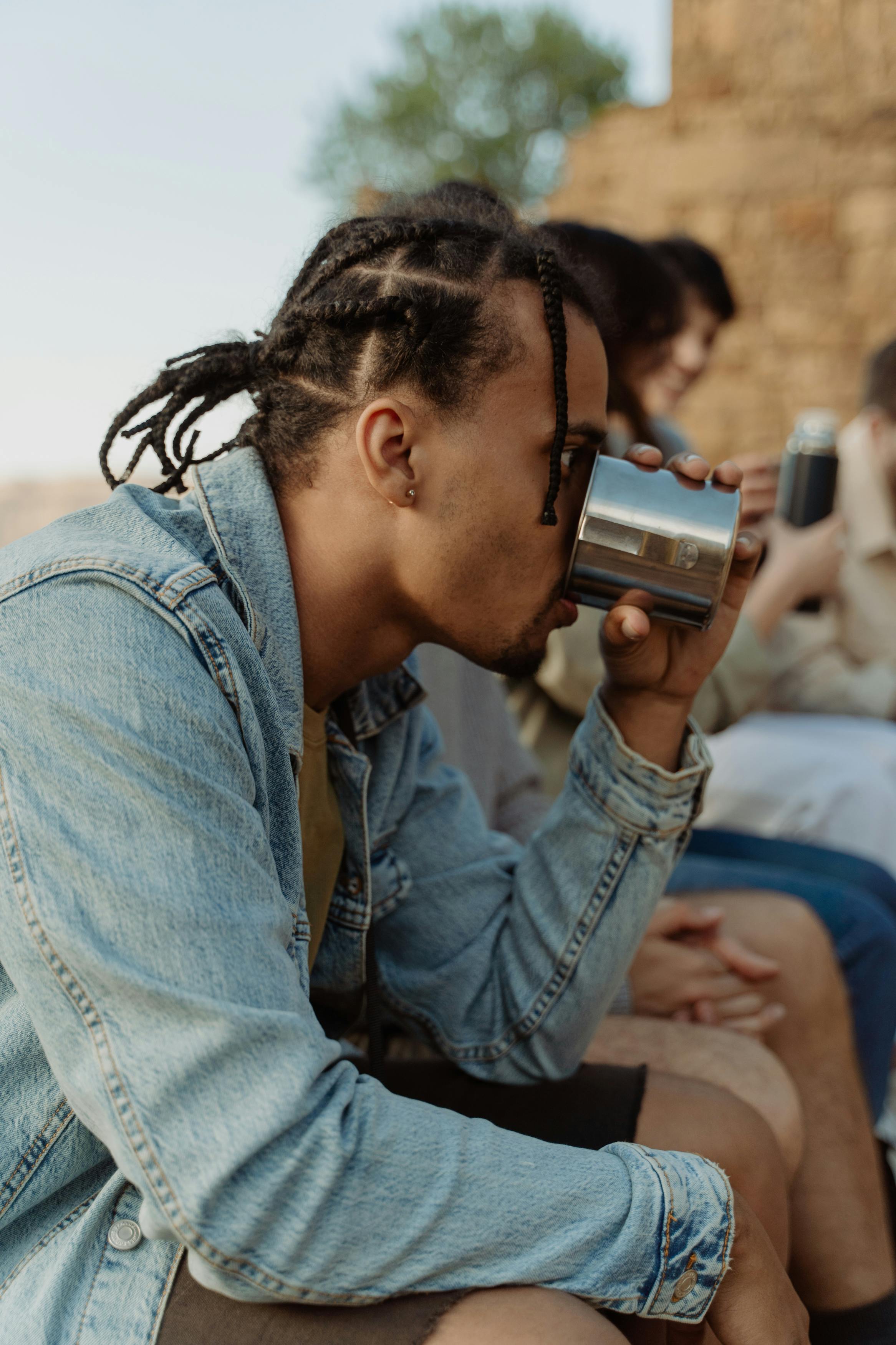 a man in denim jacket drinking water on a glass