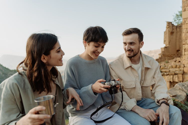 A Group Of People Sitting On Rocks With A Camera