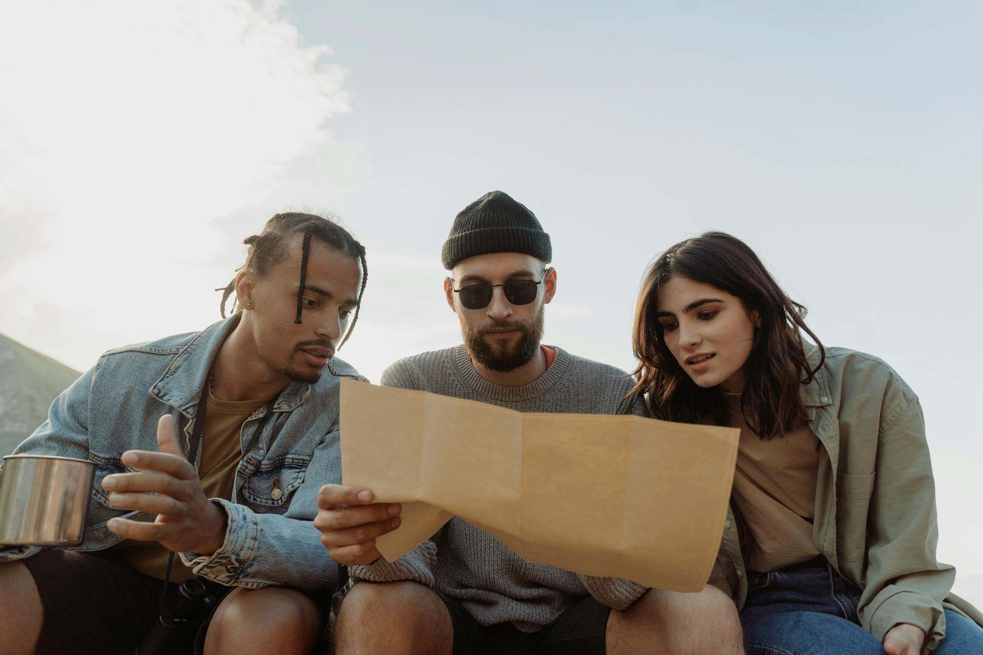 Group of diverse friends reading a map outdoors, exploring and planning their adventure.