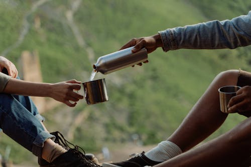 A Person Pouring Water on a Stainless Mug