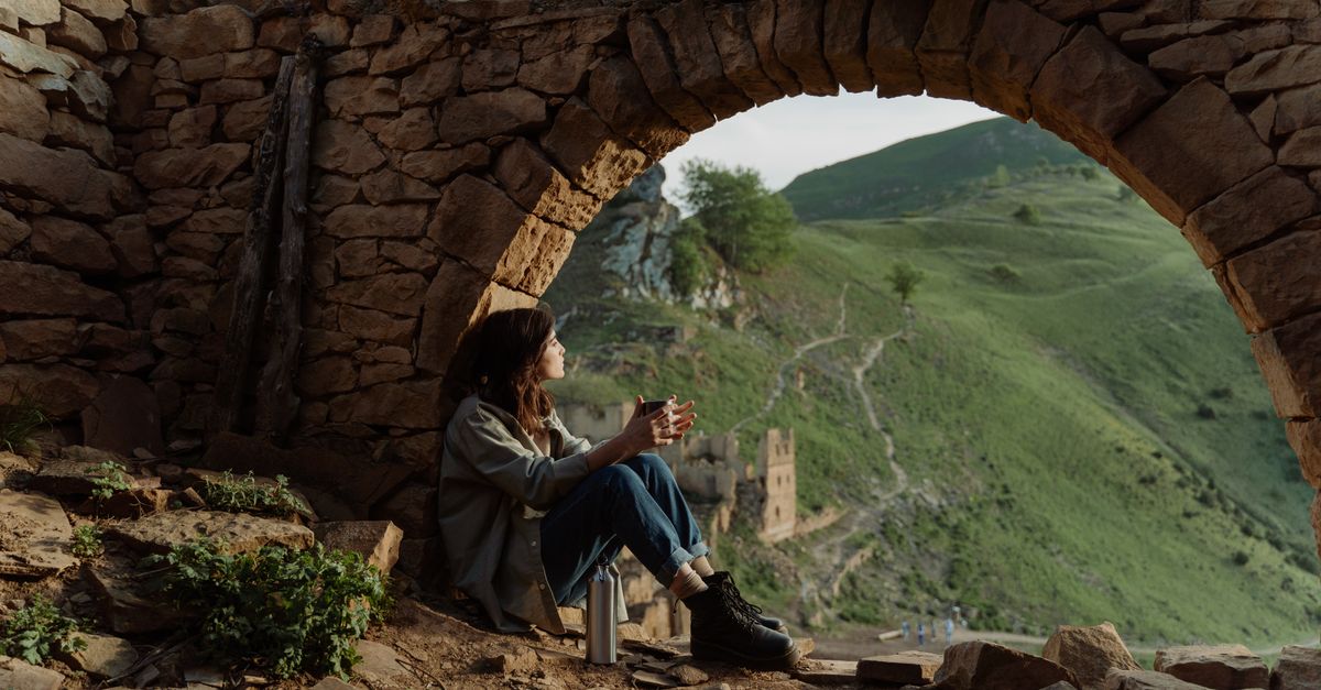 Person Looking Under Rocks A Woman in Denim Jeans Sitting Under the Rock Formation while Looking ...