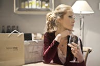 一位年轻女子衣着优雅，在米兰的一家餐厅里品着葡萄酒