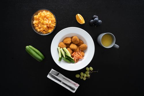 Free Healthy meal with chicken nuggets, fruits, and vegetables arranged on a black background. Stock Photo