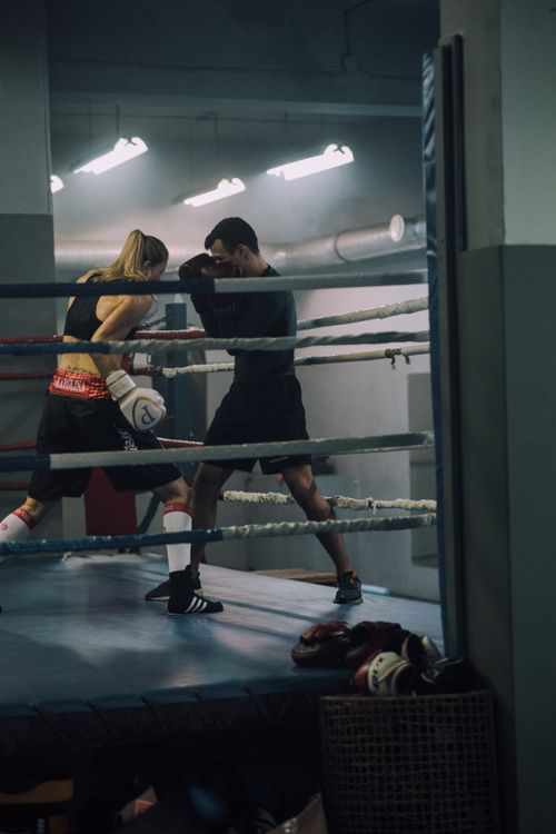 Free Intense sparring session between male and female boxers in an indoor gym. Stock Photo