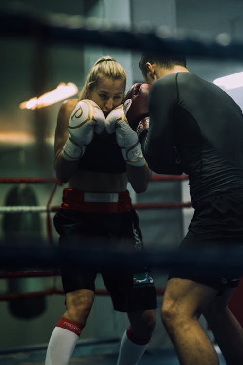 A Man and a Woman Sparring on a Boxing Ring