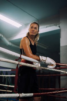 Focused female boxer standing in a boxing ring during training, exuding strength and determination.