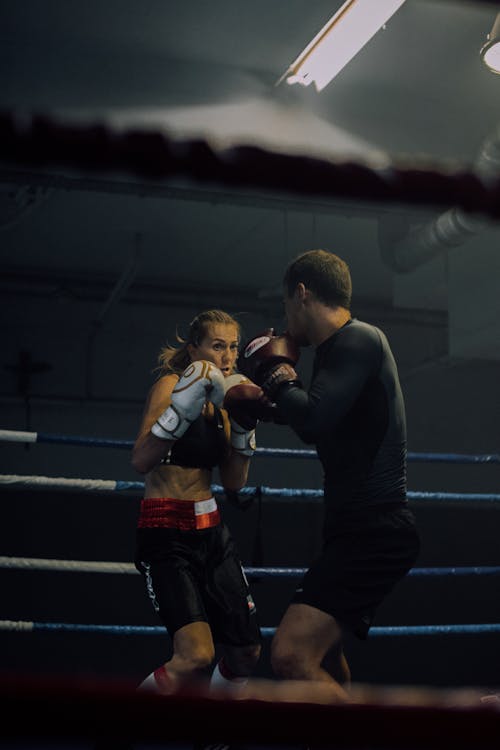 A Woman Being Trained by a Man Inside the Boxing Ring