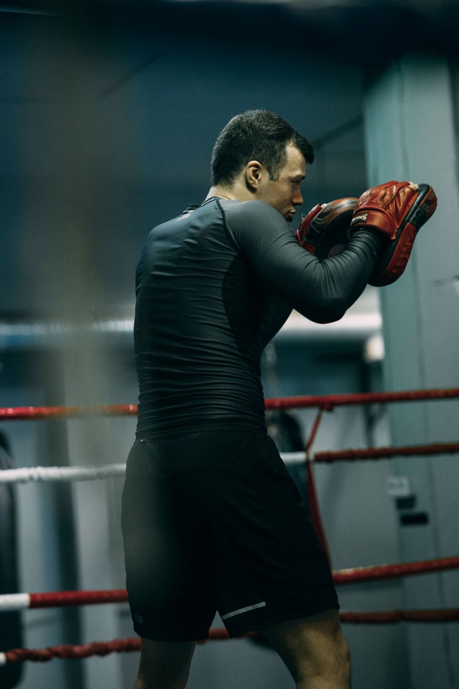 Boxer training with red gloves in a dark gym