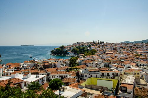 Free A picturesque coastal village with red-tile roofs overlooking the serene sea under a clear blue sky. Stock Photo