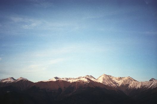 A breathtaking view of snow-capped mountain peaks under a clear blue sky in the Krasnodar Krai region of Russia.