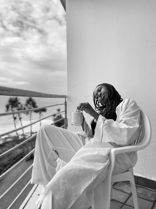 A Woman in Pajamas Sitting on a Chair at the Balcony