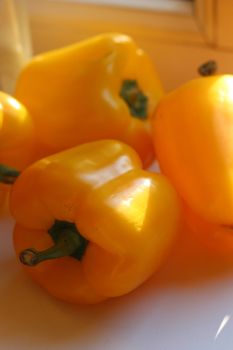 Vibrant yellow bell peppers on a sunlit surface, showcasing organic freshness.