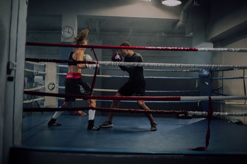 Free A man and woman spar in an indoor boxing ring, showcasing strength and athleticism. Stock Photo