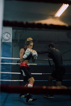 Two adult boxers sparring in a dimly lit boxing gym.