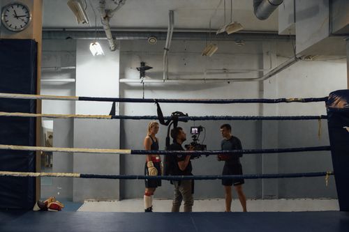 Free Boxing training scene in an industrial gym with athletes and a videographer capturing the action. Stock Photo