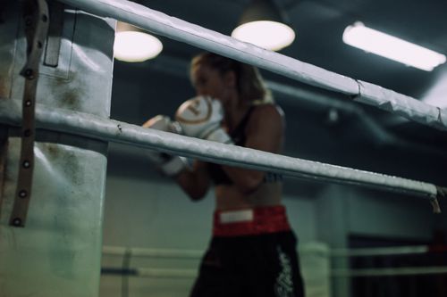 Free Focused female boxer shadow boxing in an indoor gym under ambient lighting. Stock Photo
