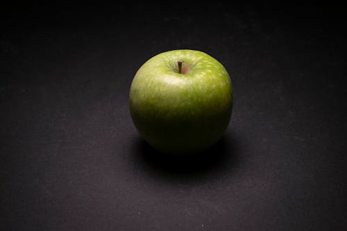 Close-Up Photo of a Green Apple on a Black Surface