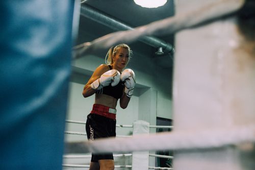 Free Female boxer poised in the ring, ready for a match, inside a boxing gym. Stock Photo
