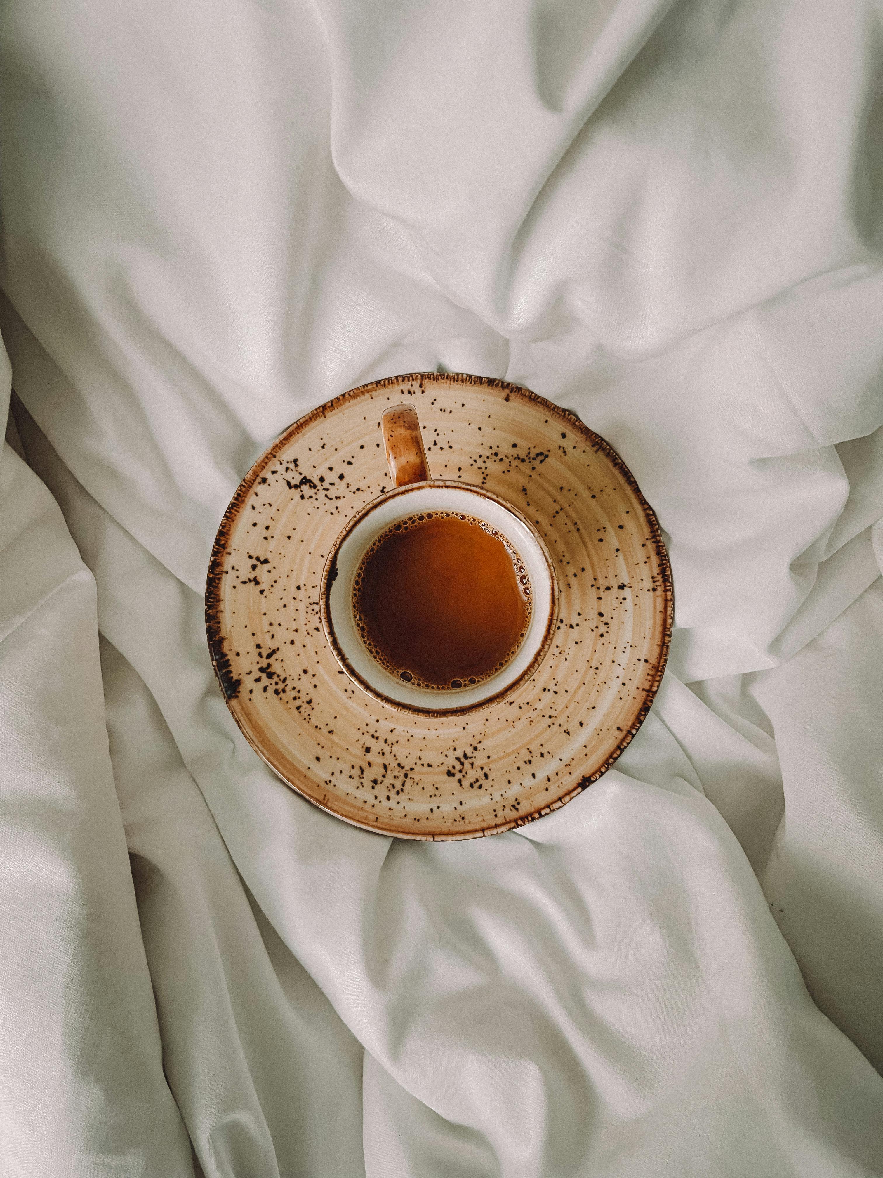 A cozy rustic brown coffee cup filled with drink on soft white cloth, symbolizing relaxation.