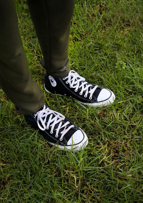 Free Black sneakers with white laces on grass, showcasing casual outdoor style. Stock Photo