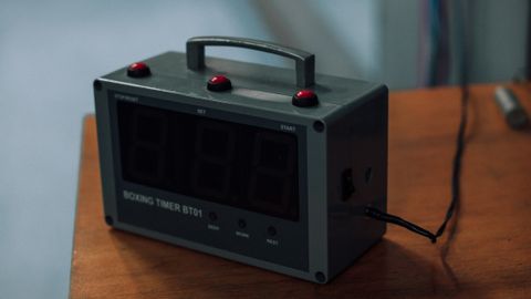 Focused view of an electronic boxing timer on a wooden surface, ideal for sports themes.