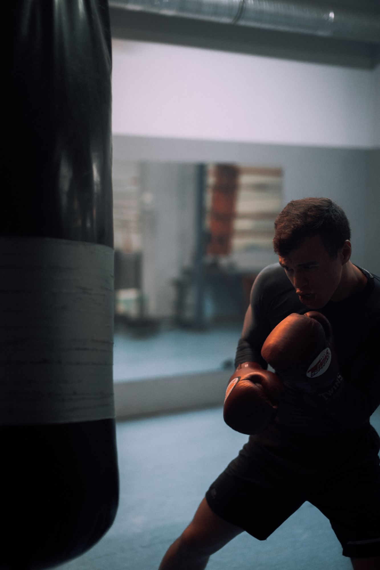 Athlete striking a heavy bag in a dark training gym