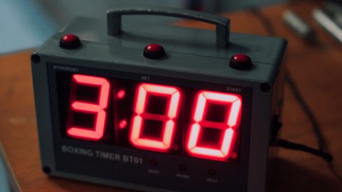 Close-up of an electronic boxing timer displaying three minutes with a red LED screen.