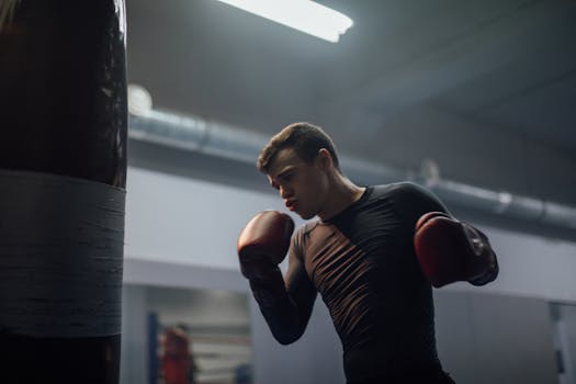 Adult male boxer practicing punches on a heavy bag in a gym environment.