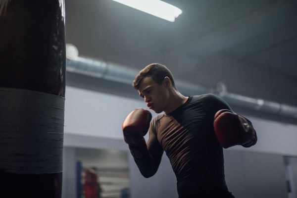 Boxer working the heavy bag in a dark gym