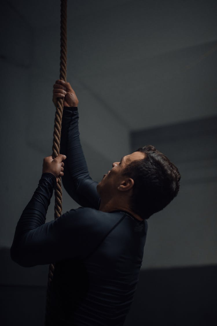 A Man Holding On A Rope While Looking Up