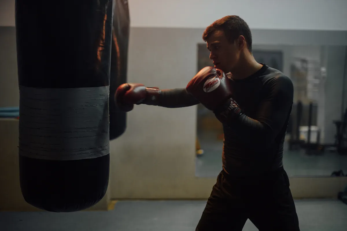 Pria memakai sarung tinju saat berlatih combat di ring boxing