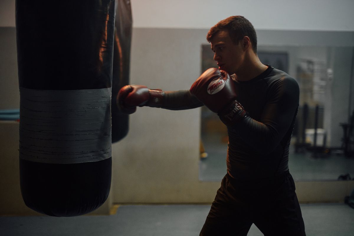 Pria memakai sarung tinju saat berlatih combat di ring boxing