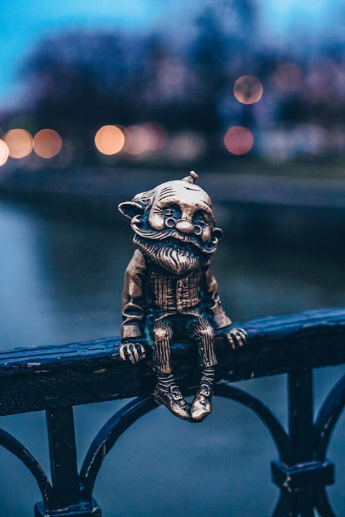 Gold Figurine on Black Metal Railing 