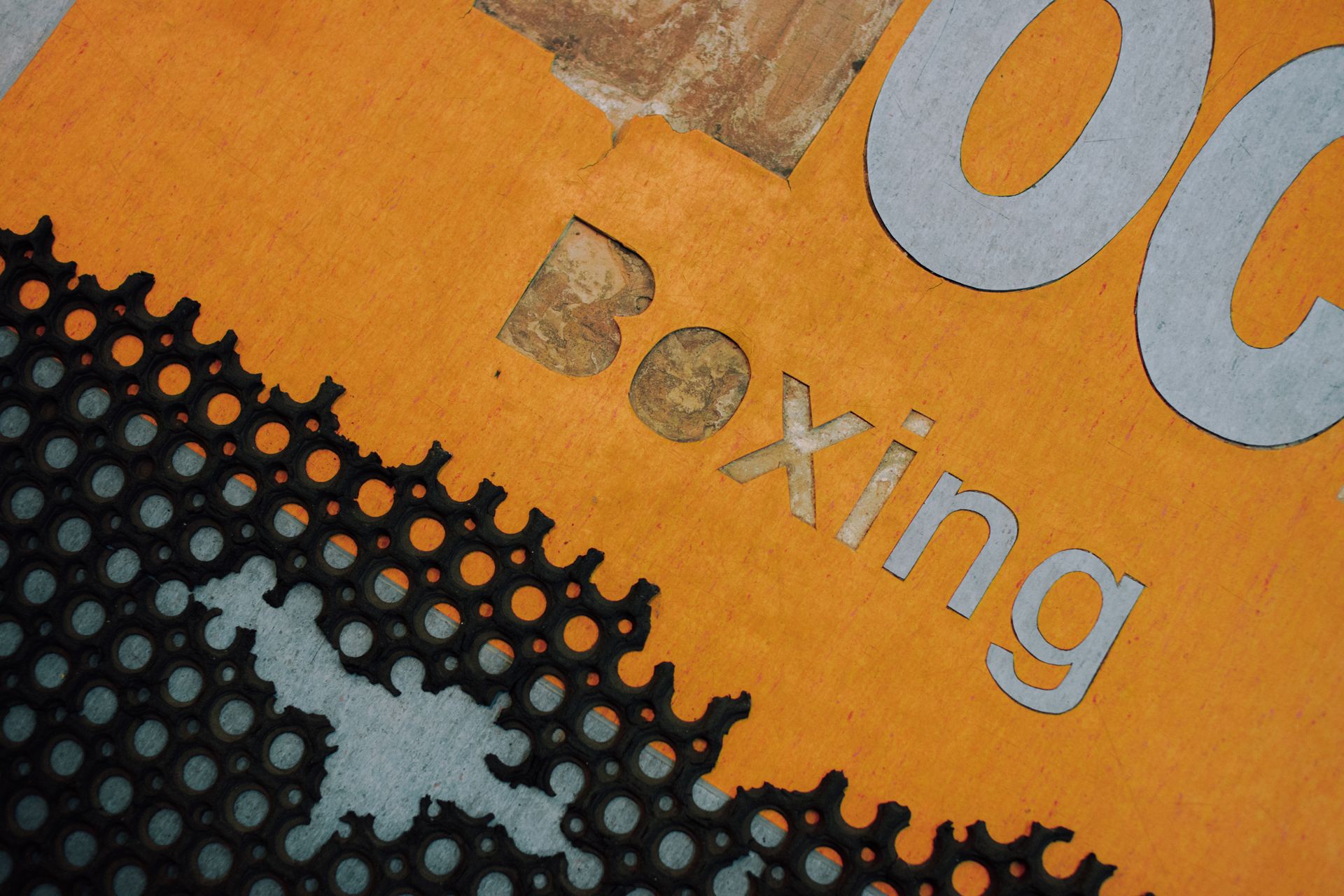 Close-up of a textured surface with cutout letters spelling 'Boxing' in an abstract design.
