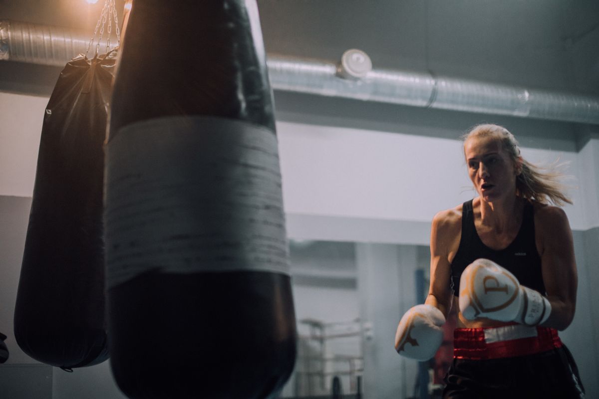 A força de continuar mesmo depois das dificuldades Mulher treinando boxe diante de um saco de pancadas com expressão determinada