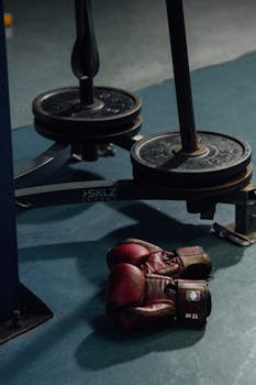 Boxing gloves lie near weight plates in a gym, highlighting fitness and training essentials.