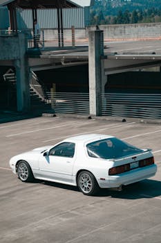 A sleek white sports car parked in an empty multi-level parking lot under daylight.