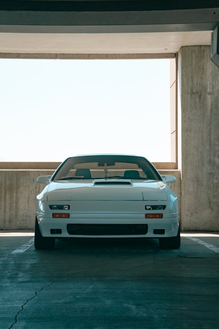 Front View Of White Car Parked In Empty Parking Lot