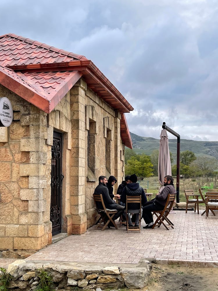 Men Sitting At Restaurant Patio In Mountains