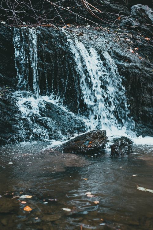 Free A serene waterfall gently cascades over rocks, surrounded by nature. Stock Photo